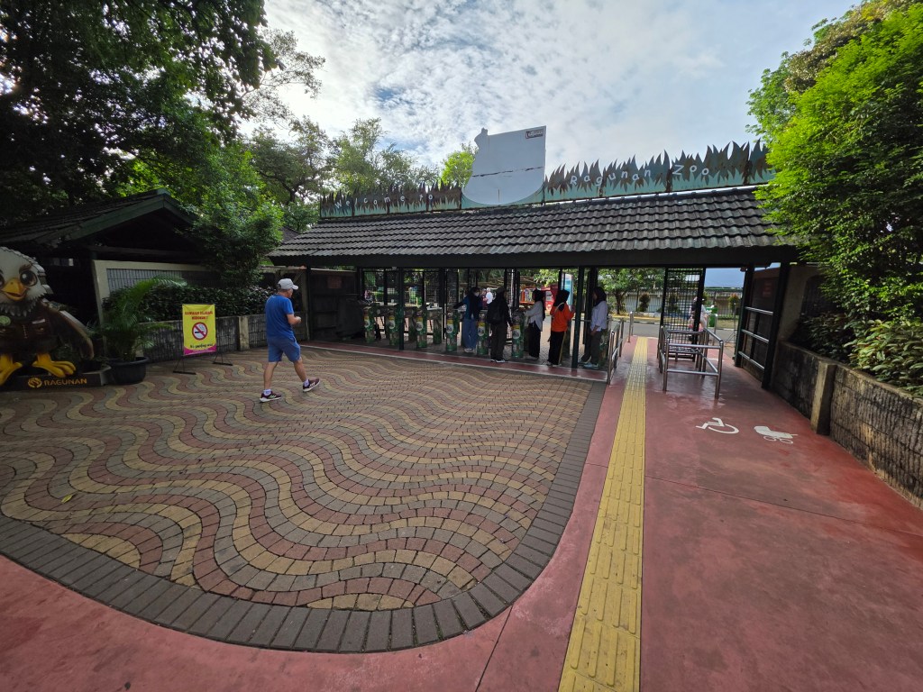 Entrance to Ragunan Zoo in Jakarta, with visitors lined up at the gate on a warm day.